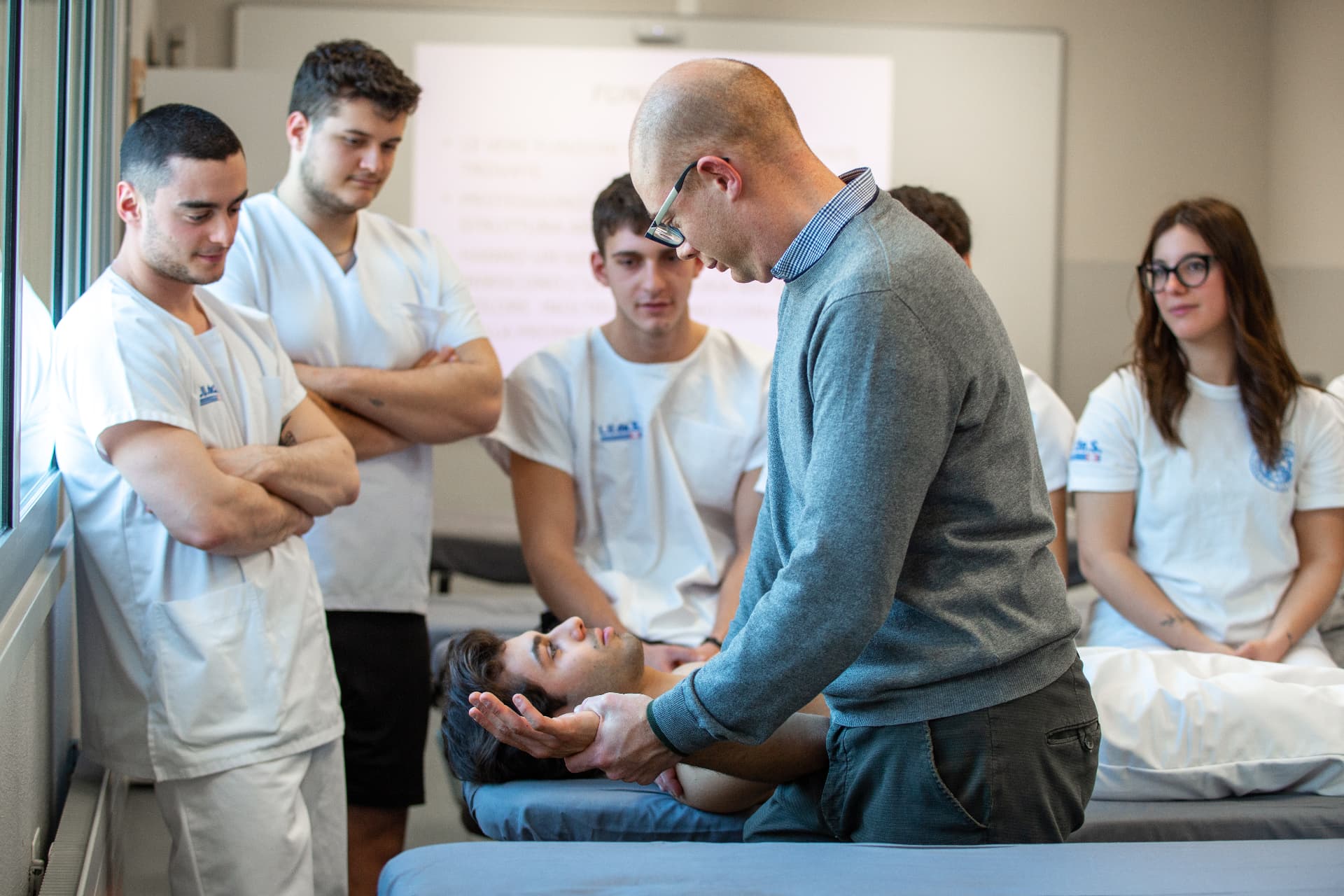 Lezione pratica di fisioterapia con docente e studenti Ludes